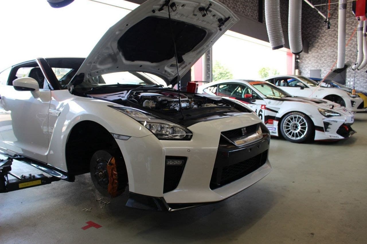 White Nissan GT-R being inspected with its hood open in the HM-R workshop
